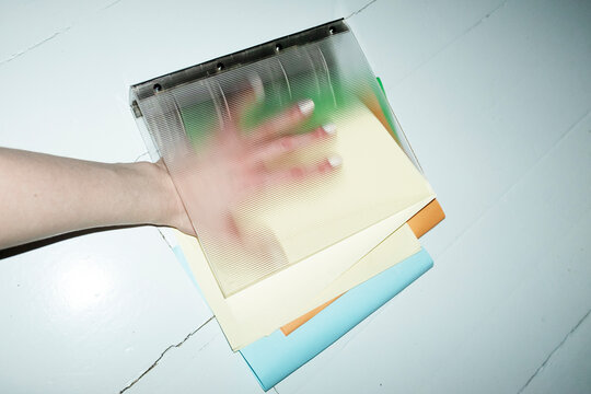 Person holding stylish folder binder full of colorful papers in office