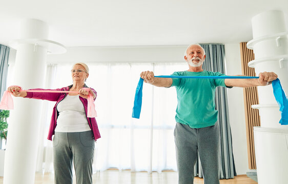 Senior couple exercise stretching and exercising with resistance band at home, health care and rehabalitation recovery concept