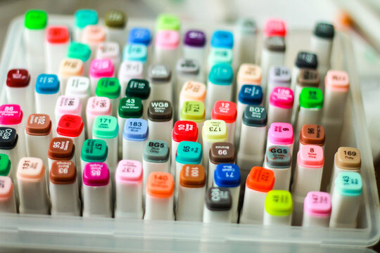 Set of professional colorful alcohol markers for sketching and drawing. Top view of vibrant multi-colored art supplies, stationery and tools for designers and artists.