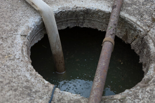 The process of pumping dirty water or a septic tank through an open concrete manhole using a special flexible hose. Municipal or private plumbing works for sewer cleaning and cesspool maintenance.