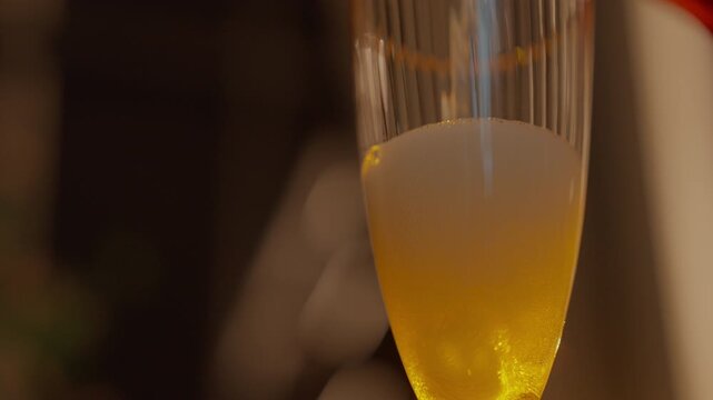 Slow motion close up of white wine pouring into glass with sparkling gold bubbles texture and natural droplet splash under warm light b-roll