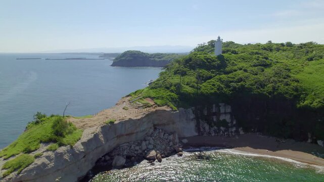 白い灯台と海食洞が美しい加佐の岬 日本海の絶景 空撮 左旋回 / Aerial drone orbiting left showing the white lighthouse and sea caves of Cape Kasa, Sea of Japan