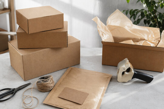 Cardboard packaging workspace with shipping boxes kraft mailer twine scissors and tape dispenser