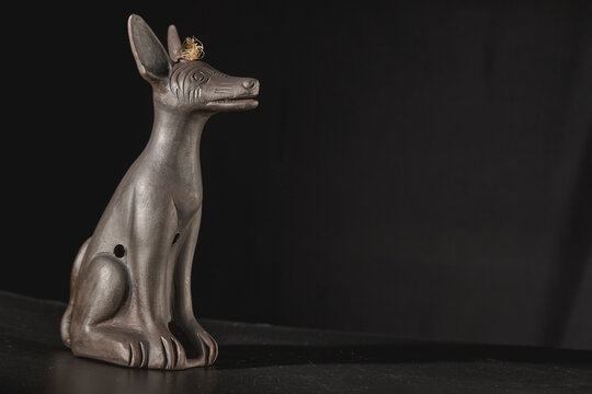 Xoloitzcuintli mexican hairless dog ceramic sculpture against dark background