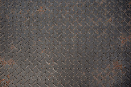 Dark rusty diamond plate metal texture. Industrial steel floor pattern with rust spots. Grunge heavy metal background for construction.