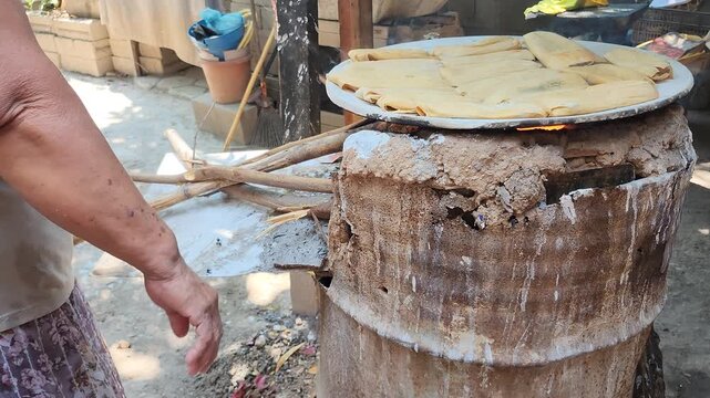 Indigenous Woman Hands Turning Traditional Tamales on Clay Comal Griddle