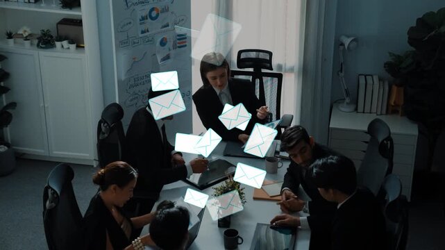 Group of business professionals in a modern office environment discussing email correspondence with floating envelope icons representing digital communication. Entropy.