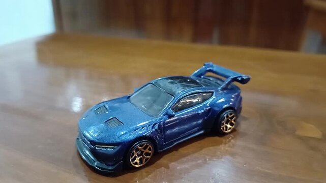Blue sports car rests on wooden surface