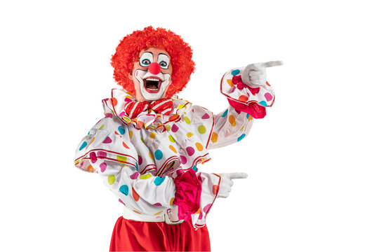 Funny clown pointing at blank template copy spase for advertising, posters, greetings, invitations. Entertainer as Joker in a suit and wig, with clown whiteface makeup.