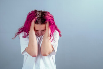 Naklejka premium Young woman with pink hair holding her head in distress. Concept of stress, anxiety, depression, emotional overload, and mental health.