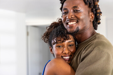 Obraz premium African American couple embracing, smiling at home, man with nose ring, woman showing stud earrings