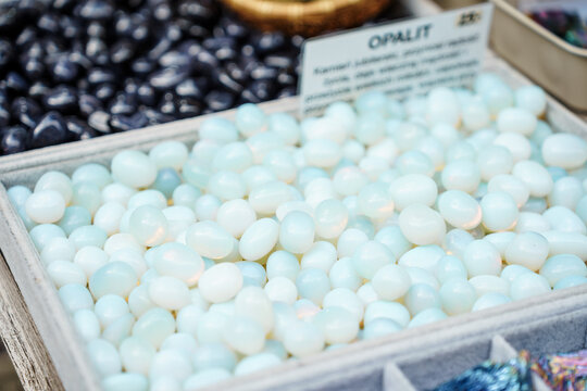 Polished light blue opalite gemstones displayed in a tray for sale at a local market