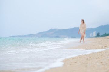 Fototapeta premium blurred woman in boho beach clothes walking along beach enjoying vacations
