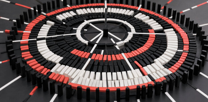 Abstract circular arrangement of black white and red domino tiles on a dark surface with dominoes abstract strategy alignment conceptual sequence standing geometry precision business