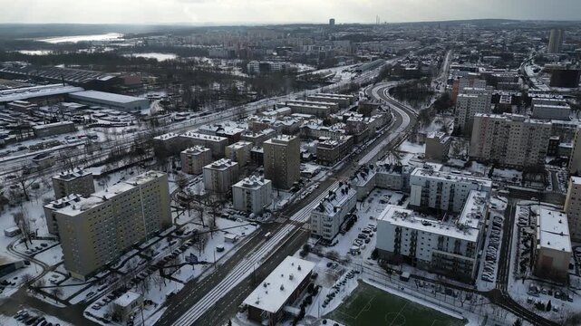 Aerial view of a snow-covered city neighborhood with a green football pitch and apartment buildings in winter, Katowice, Poland.
