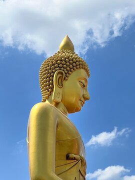 Giant golden Buddha statue at Wat Paknam against blue sky