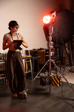 Photographer checking camera settings beside studio light