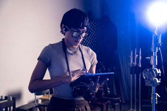 Photographer using tablet on studio set with blue lighting