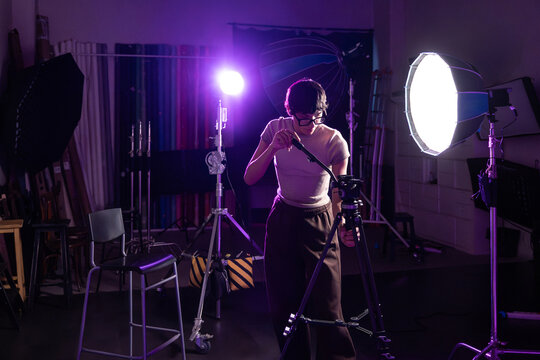 Photographer adjusting tripod in studio with bright lights