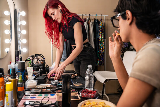 Makeup artist organizes kit as staff snack backstage