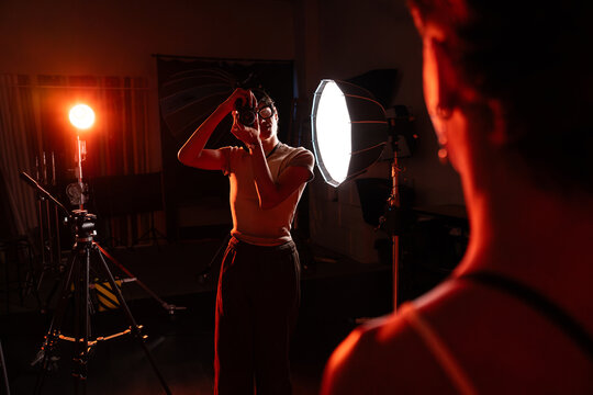 Studio photographer directing model during moody photoshoot