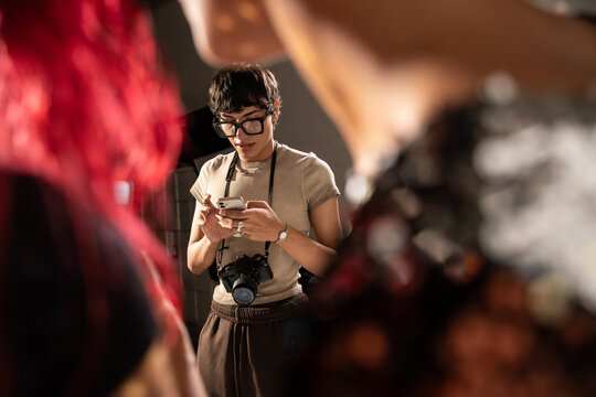 Photographer texting on smartphone with camera on studio set