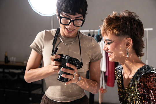 Fashion photographer showing camera to model on set