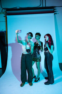Fashion photoshoot crew celebrating with selfie and drinks