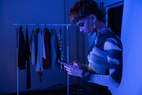 Backstage studio model checking phone near clothing rack