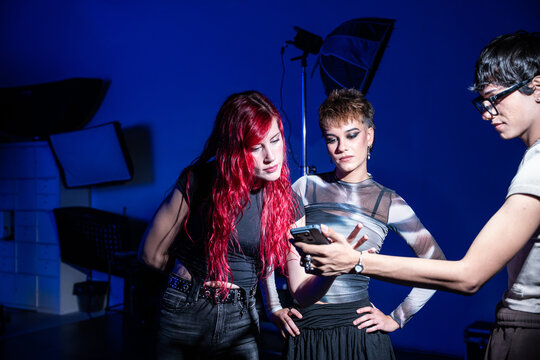 Fashion studio team reviewing photos on smartphone set