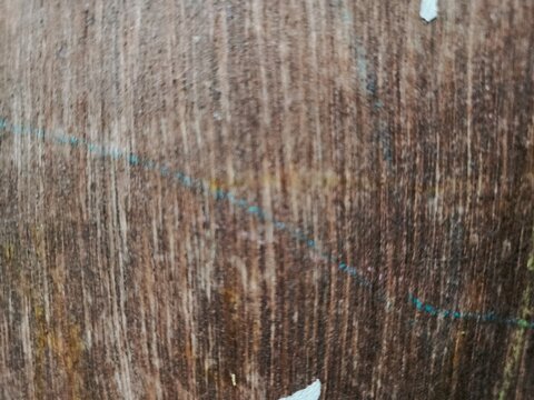 Close-up selective focus of an old brown multiplex wood surface featuring vertical grain patterns, natural wear, and a subtle blue crayon scribble line. Ideal as an abstract industrial background, rus
