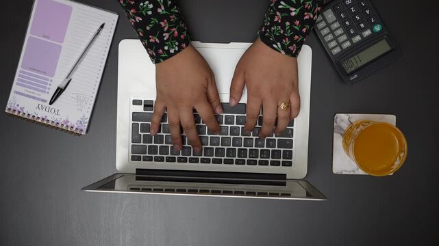 Top Down View of Woman Opening Laptop and Typing on Keyboard at Desk