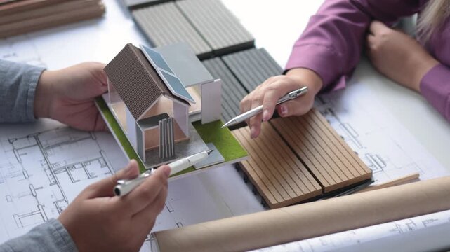 Professional architect and designer collaborating on floor plans and flooring material samples.