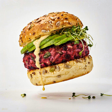 floating gourmet vegan plant-based burger with avocado and beetroot patty on white background