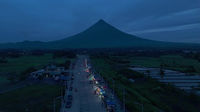 Aerial view of Mayon Volcano towering above bypass road at blue hour. Ideal for travel and tourism.