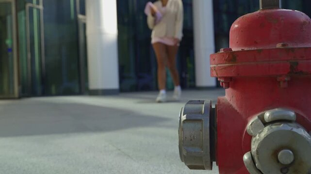 Successful businesswoman walking on a sidewalk past a red fire hydrant in a modern city