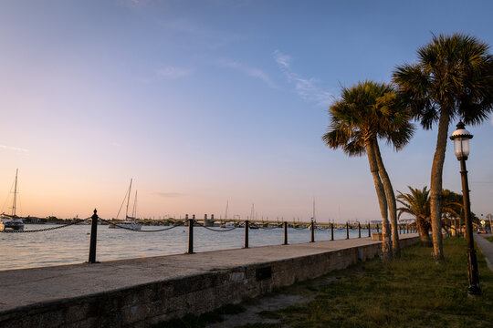 Sunrise and Sunset Over Historic St. Augustine, Florida. Castillo de San Marcos Silhouette with Palm Trees, Sailboats, and Bridge of Lions Reflecting on Matanzas Bay