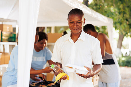 Multiracial hunger relief organization operating outside to provide homeless people with free meals and necessities. Nonprofit group help the needy and the less fortunate with fruits and warm food.