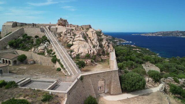 Sardynia - Włochy
Fortezza di Monte Altura forteca starożytna na szczycie g&oacute;ry. Ładne ujęcie nagrane dronem z pięknymi widokami na fortece, morze, g&oacute;ry