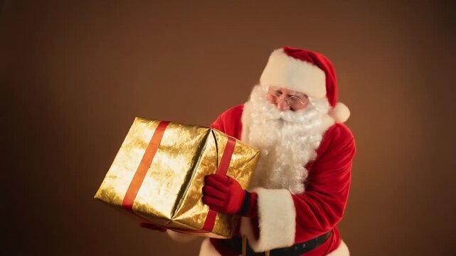Santa Claus, dressed in his iconic red suit and hat, joyfully presents a large, shimmering golden gift box tied with a red ribbon.