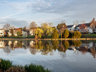 Fototapeta premium Lakeside suburban houses in Ashburn Village with spring foliage reflections