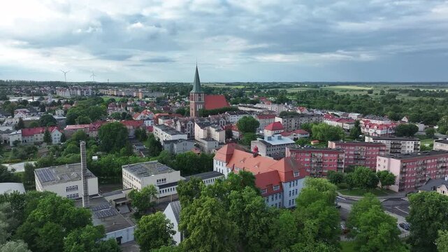 Aerial Drawsko Poland city church climb 2. Overhead of historic agricultural based town and economy. Neighborhood, homes, apartments and city village business. Old church in market square. European.