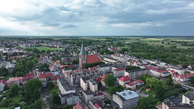 Aerial Drawsko Poland city church climb 3. Overhead of historic agricultural based town and economy. Neighborhood, homes, apartments and city village business. Old church in market square. European.