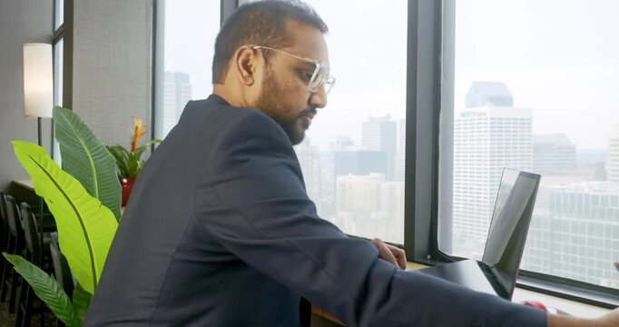 Businessman working on laptop in high-rise office