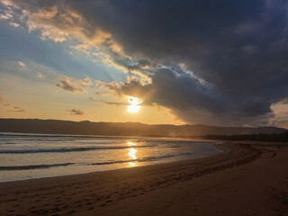 Obraz premium Dramatic Sunset Over Tropical Beach with Dark Storm Clouds
