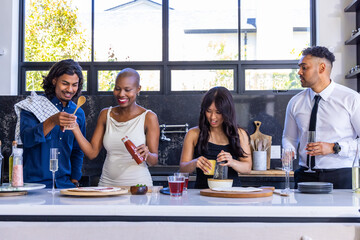 Diverse friends chopping, seasoning and grating at kitchen island with squeeze bottle and flute © wavebreak3