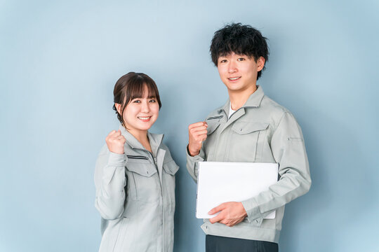 ガッツポーズする作業着を着たブルーカラーの男女スタッフ