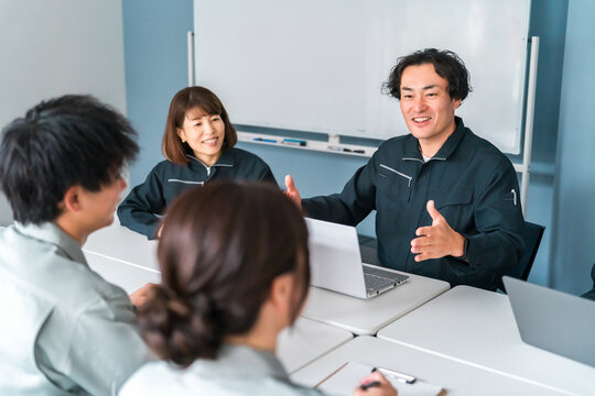 オフィス,事務所でミーティング,打ち合わせする作業着姿の男女の従業員