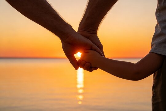 Hands holding at sunset by water