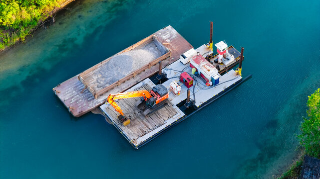 Dredging operation on industrial barge with excavator moving sand